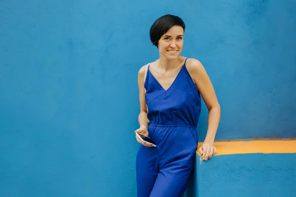 Woman in blue clothes on bright blue background in the city.