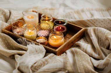 Yatakta sıcak ekose ile ahşap tepsi üzerinde mum yakma. İskandinav tarzı. Hygge kavramı.