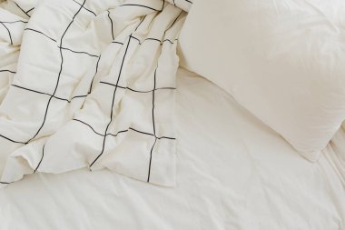 Çizgili battaniye ve yastık ile beyaz yatak çarşafları. Dağınık yatak. 