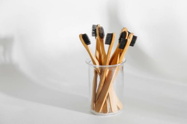 Ahşap Eko bambu diş fırçası ile cam beyaz arka planda siyah kıl. Sürdürülebilir bir yaşam tarzı. Sıfır atık kavramı.