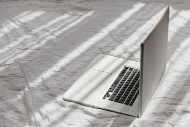 Evde konsept beyaz yatak üzerinde Laptop iş. Sabah ışığı