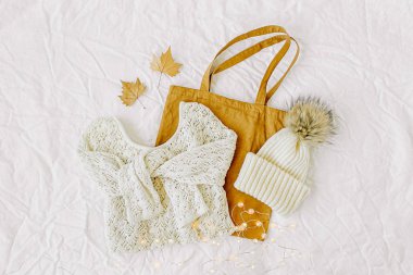 Tote çanta ve süslemeleri ile örme beyaz kazak. Beyaz arka plan üzerinde Sonbahar moda giysiler kolaj. Üst görünüm düz yatıyordu. 