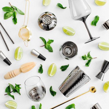 Kokteyl yapmak için bar aksesuarları. Titretici, jigger, cam, kaşık ve arka planda kireç ve nane yapraklı diğer bar araçları. 