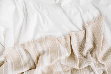 Sıcak ekoseli beyaz yatak. Kopyalama alanı olan rahat bir arkaplan. İskandinav tarzı. Düz yatış, üst görünüm