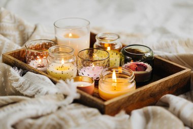 Yatakta sıcak ekose ile ahşap tepsi üzerinde mum yakma. İskandinav tarzı. Hygge kavramı.