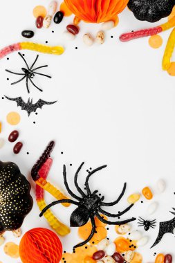 Renkli şeker, yarasalar, örümcekler, kabaklar ve beyaz arka plan dekorasyon ile Halloween tatil çerçevesi. Düz yatıyordu. Yukarıdan görüntüle