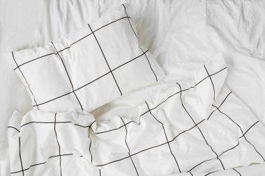 White bedding sheets with striped blanket and pillow. Messy bed. Cozy background. clipart