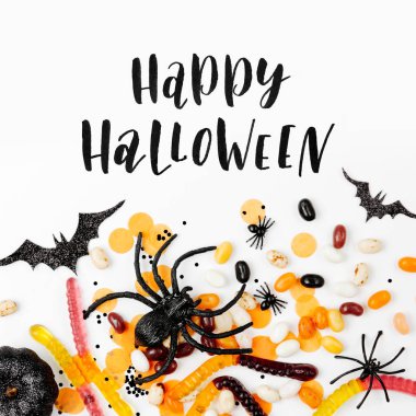 Cadılar Bayramı tatil süslemeleri, renkli şeker, yarasalar, beyaz arka plan örümcekler. Düz döşeme, üst görünüm 