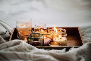 Yatakta sıcak ekose ile ahşap tepsi üzerinde mum yakma. İskandinav tarzı. Hygge kavramı.