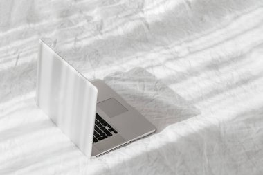 Evde konsept beyaz yatak üzerinde Laptop iş. Sabah ışığı. Yaşam Tarzı Concep