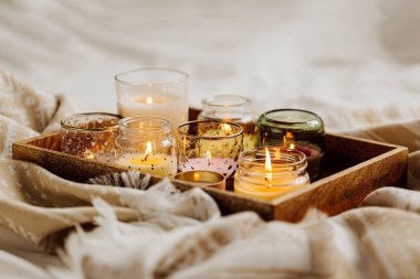 Yatakta sıcak ekose ile ahşap tepsi üzerinde mum yakma. İskandinav tarzı. Hygge kavramı.