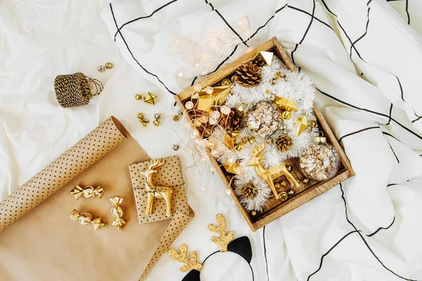 白色床上的木箱中装有圣诞装饰品和礼物 配有毯子 假日理念 顶视图 — 图库照片