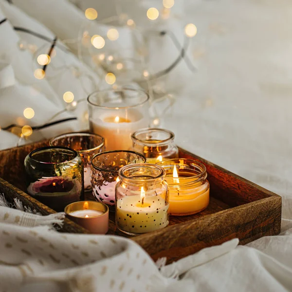 Yatakta sıcak ekose ile ahşap tepsi üzerinde mum yakma. İskandinav tarzı. Hygge kavramı.