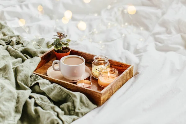 咖啡和蜡烛托盘与温暖的格子在白色床上用品 早餐在床上 斯堪的纳维亚风格 顶视图 — 图库照片
