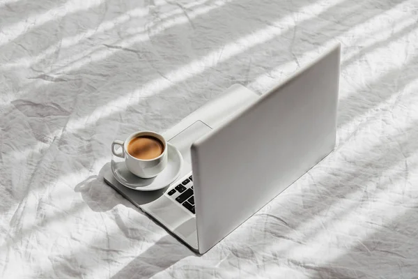 Laptop ve kahve beyaz yatakta. Ev konseptinde çalış. Sabah ışığı 