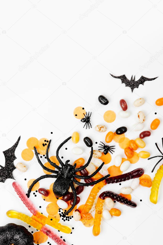 Halloween holiday decorations, colorful candy, bats, spiders  on white background. Flat lay, top view 