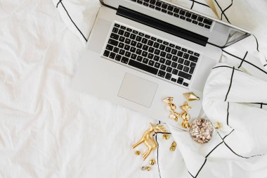 Dizüstü bilgisayar ve Noel süslemeleri ile yatakta Çalışma Alanı. Tatil konsepti. Düz döşeme, üst görünüm