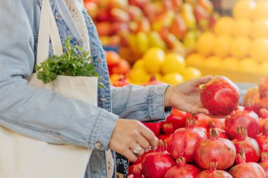 Kadın gıda pazarında meyve ve sebze seçer. Alışveriş için yeniden kullanılabilir eko çanta. Sürdürülebilir yaşam tarzı. Çevre dostu konsept. 