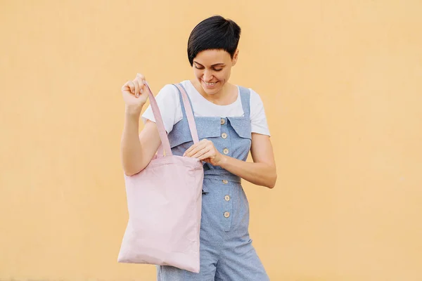 Woman holding canvas tote bag on yellow background. Reusable eco bag. Eco friendly concept.