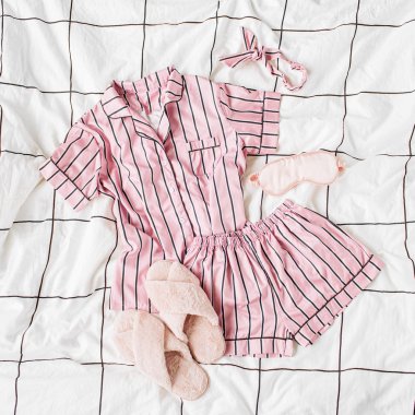 Kabarık kürk terlik ile Pijama uyku seti. Yatakta çizgili klasik pembe uyku elbisesi. Günaydın konsepti. Düz döşeme, üst görünüm