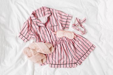 Kabarık kürk terlik ile Pijama uyku seti. Yatakta çizgili klasik pembe uyku elbisesi. Günaydın konsepti. Düz döşeme, üst görünüm