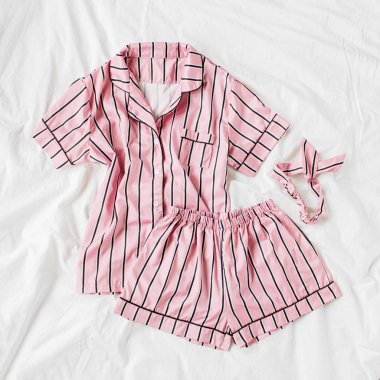 Pijama uyku seti. Yatakta çizgili klasik pembe uyku elbisesi. Günaydın konsepti. Düz döşeme, üst görünüm