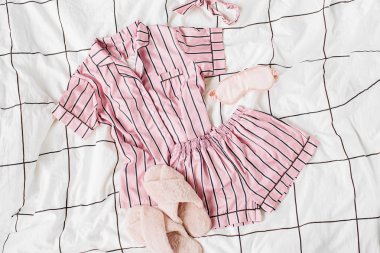 Kabarık kürk terlik ile Pijama uyku seti. Yatakta çizgili klasik pembe uyku elbisesi. Günaydın konsepti. Düz döşeme, üst görünüm