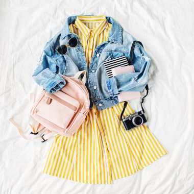 Mavi jean ceket ve sırt çantası, kitap ve beyaz fotoğraf makinesi ile Sarı elbise. Kadınların şık sonbahar veya bahar kıyafeti. Üniversite için modaya uygun kıyafetler. Okul konseptine geri dönelim. Düz döşeme, üst görünüm.