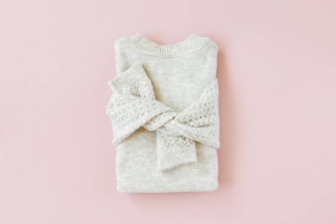 Soluk pembe arka plan üzerinde gri sıcak örme kazak. Kadın şık sonbahar veya kış lık giysiler. Düz döşeme, üst görünüm.