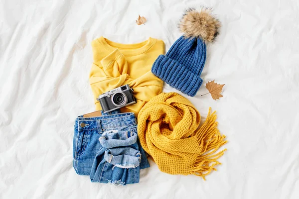 舒适的黄色毛衣 蓝色牛仔裤 围巾和帽子在床上的白床单 女士时尚的秋冬套装 时髦的服装拼贴画 顶视图 — 图库照片