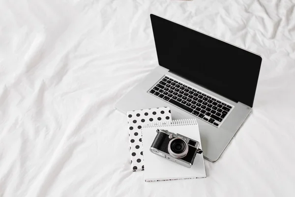 ラップトップ ノートの書き込みと自宅の概念で白いベッドの仕事のカメラ 机の作業のトップビュー — ストック写真