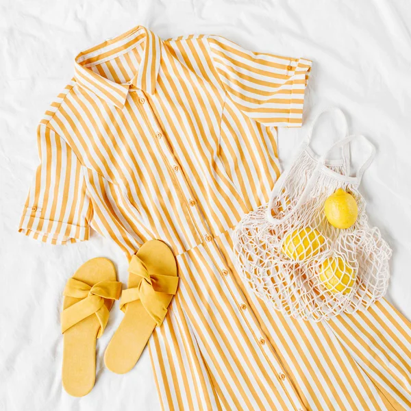 黄色连衣裙 带条纹 带生态袋和拖鞋 铺在白色床上 女装时尚的夏季服装 时髦的衣服 顶视图 — 图库照片