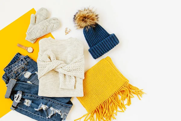 白い背景にジーンズ セーター ミトン 黄色のスカーフを持つ青い冬の帽子 女性のスタイリッシュな秋や冬の衣装 トレンディな服のコラージュ フラットレイ トップビュー — ストック写真
