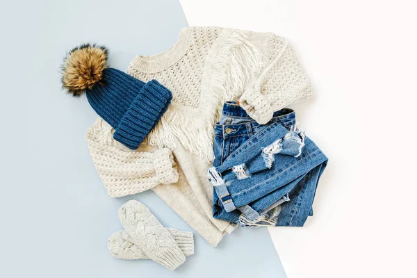 白い背景にジーンズ セーター ミトンと青い冬の帽子 女性のスタイリッシュな秋や冬の服 トレンディな服のコラージュ フラットレイ トップビュー — ストック写真