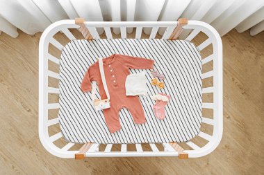 Bebek kıyafetlerinin ve beşikteki aksesuarların en üst görüntüsü. Bebek odasında yeni doğan bebek için ahşap beşik.