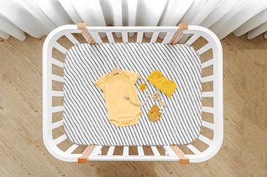 Bebek kıyafetlerinin ve beşikteki aksesuarların en üst görüntüsü. Bebek odasında yeni doğan bebek için ahşap beşik.