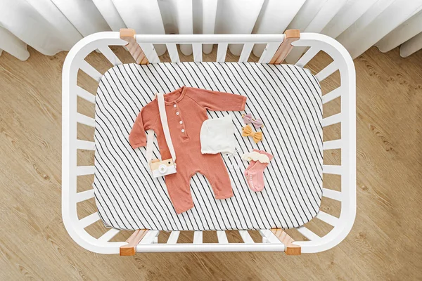 Bebek kıyafetlerinin ve beşikteki aksesuarların en üst görüntüsü. Bebek odasında yeni doğan bebek için ahşap beşik.