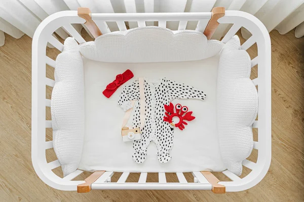 Bebek kıyafetlerinin ve beşikteki aksesuarların en üst görüntüsü. Bebek odasında yeni doğan bebek için ahşap beşik.