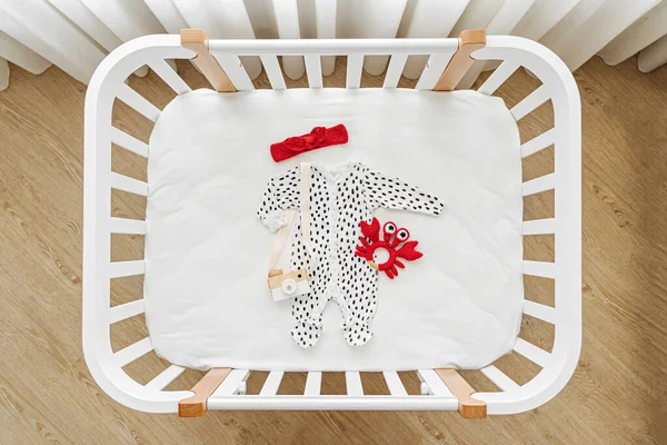 Bebek kıyafetlerinin ve beşikteki aksesuarların en üst görüntüsü. Bebek odasında yeni doğan bebek için ahşap beşik.