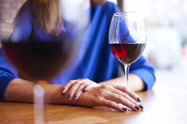 Red wine in glasses near window in cafe, chilling on vacation or holidays, bar concept. Woman hand holding a glass.