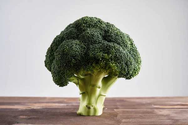 Perfect fresh broccoli on light wooden background stands as a tree. Concept of healthy food and nutrition.