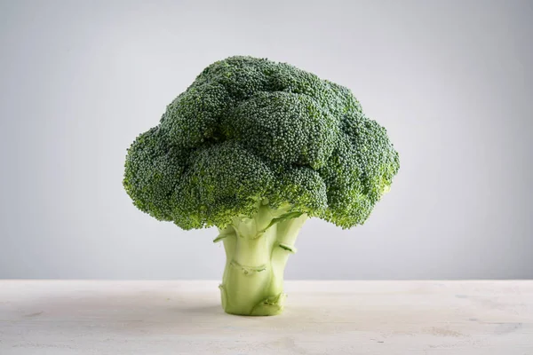 Perfect fresh broccoli on light wooden background stands as a tree. Concept of healthy food and nutrition.