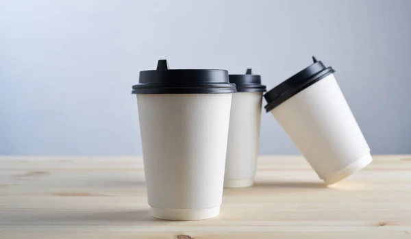 Paper coffee disposable cup for take away or to go, wooden table, space for design mock-up.