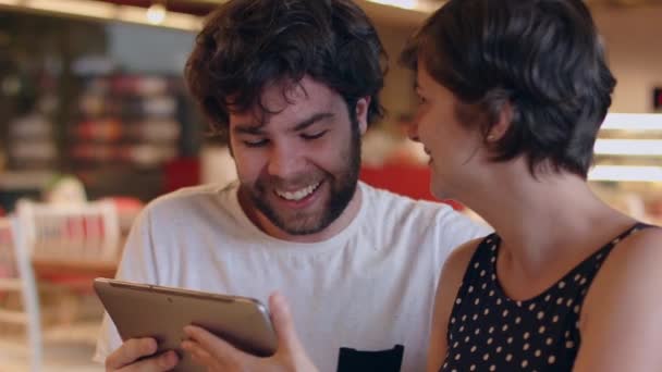 一对年轻夫妇谈论着在咖啡店里看平板电脑的应用 — 图库视频影像
