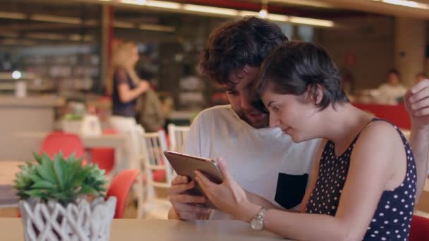 一对年轻夫妇谈论着在咖啡店里看平板电脑的应用 — 图库视频影像