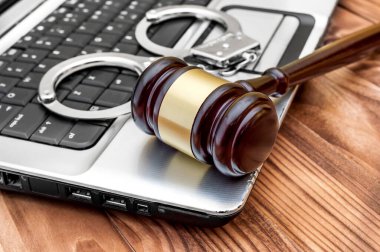 Üzerinde tokmak ve kelepçe olan bir dizüstü bilgisayar. İnternet suçu kavramı. 