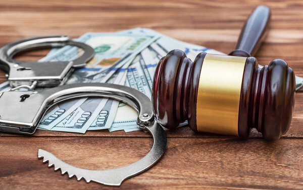 Gavel with handcuffs and money on the wooden table. Crime and law concept.