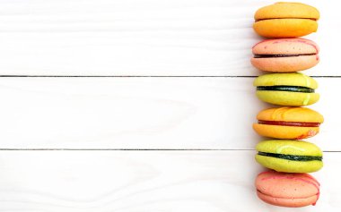 Beyaz ahşap arka planda renkli badem kurabiyeleri. Üst Manzara. Metin için boşluk.