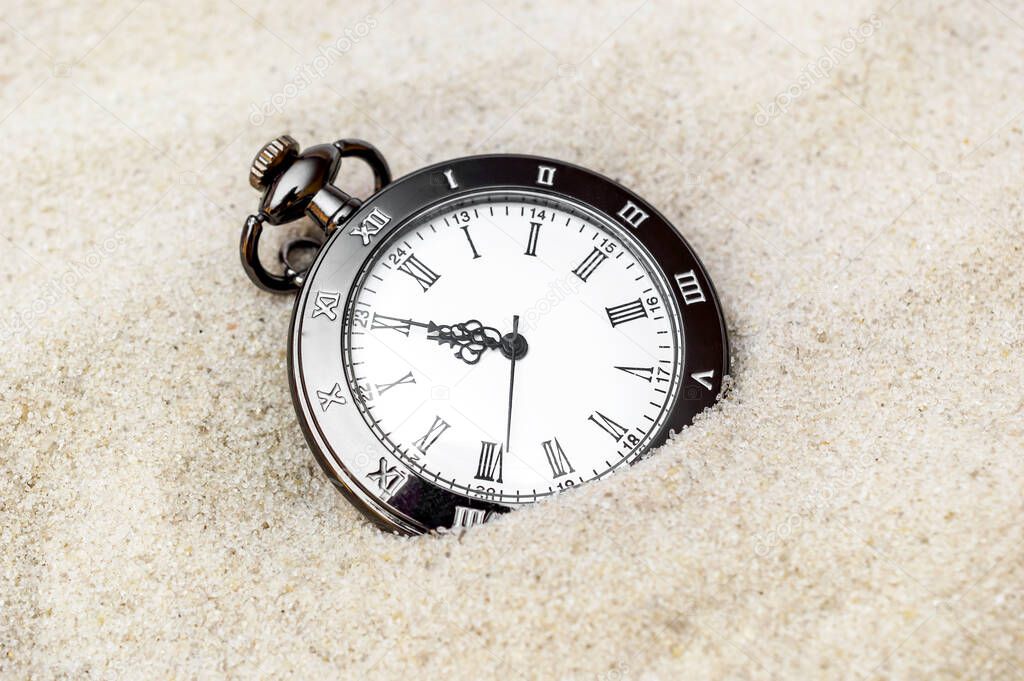 Pocket watch on the sand. Close up.