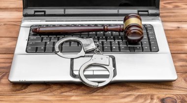 Üzerinde tokmak ve kelepçe olan bir dizüstü bilgisayar. İnternet suçu kavramı. 